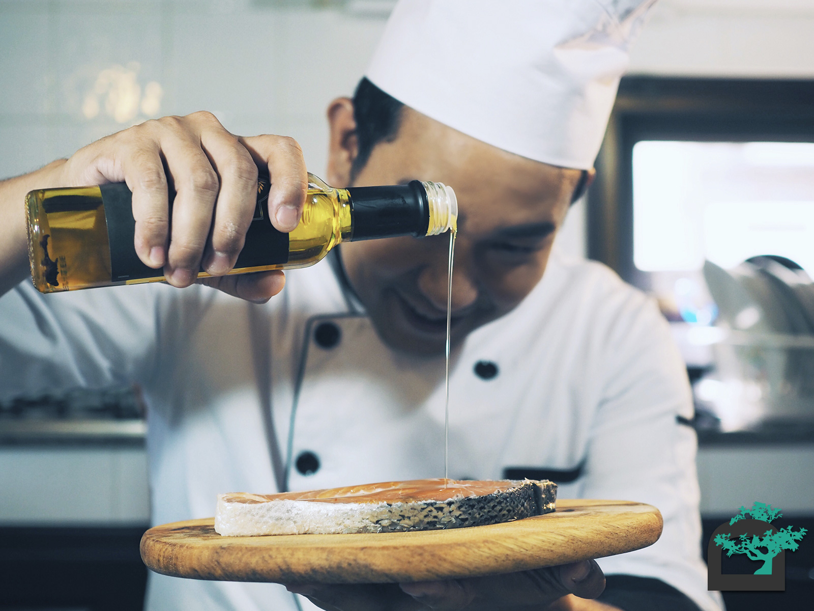 Chef vertiendo aceite de oliva sobre una rodaja de salmón.